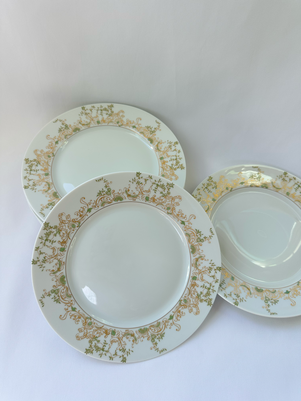 Three Haviland Limoges Chambord plates arranged together on a white background, showing the repeated green and gold pattern.
