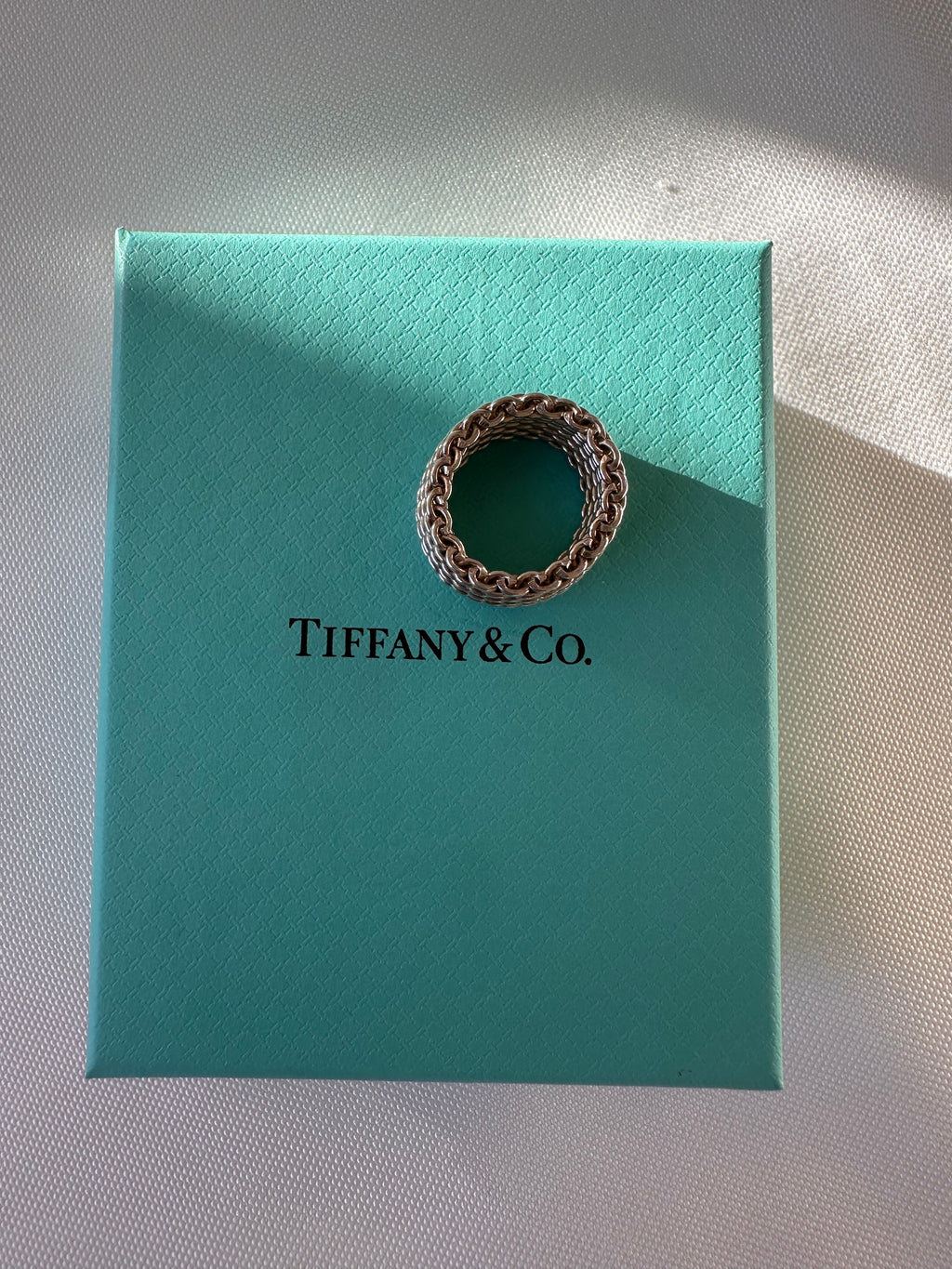 Overhead view of the silver mesh ring on a turquoise Tiffany & Co. box, showing the circular opening.
