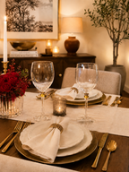 Two Luminarc France wine glasses in a warmly lit dining table set for two, featuring white plates, gold charger plates, gold flatware, folded white napkins with gold rings, and a red rose floral arrangement in a glass vase.