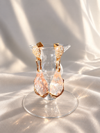 Alexis Bittar Liquid Lucite crystal pavé drop earrings displayed front-facing on a clear glass stand against a soft neutral fabric backdrop.