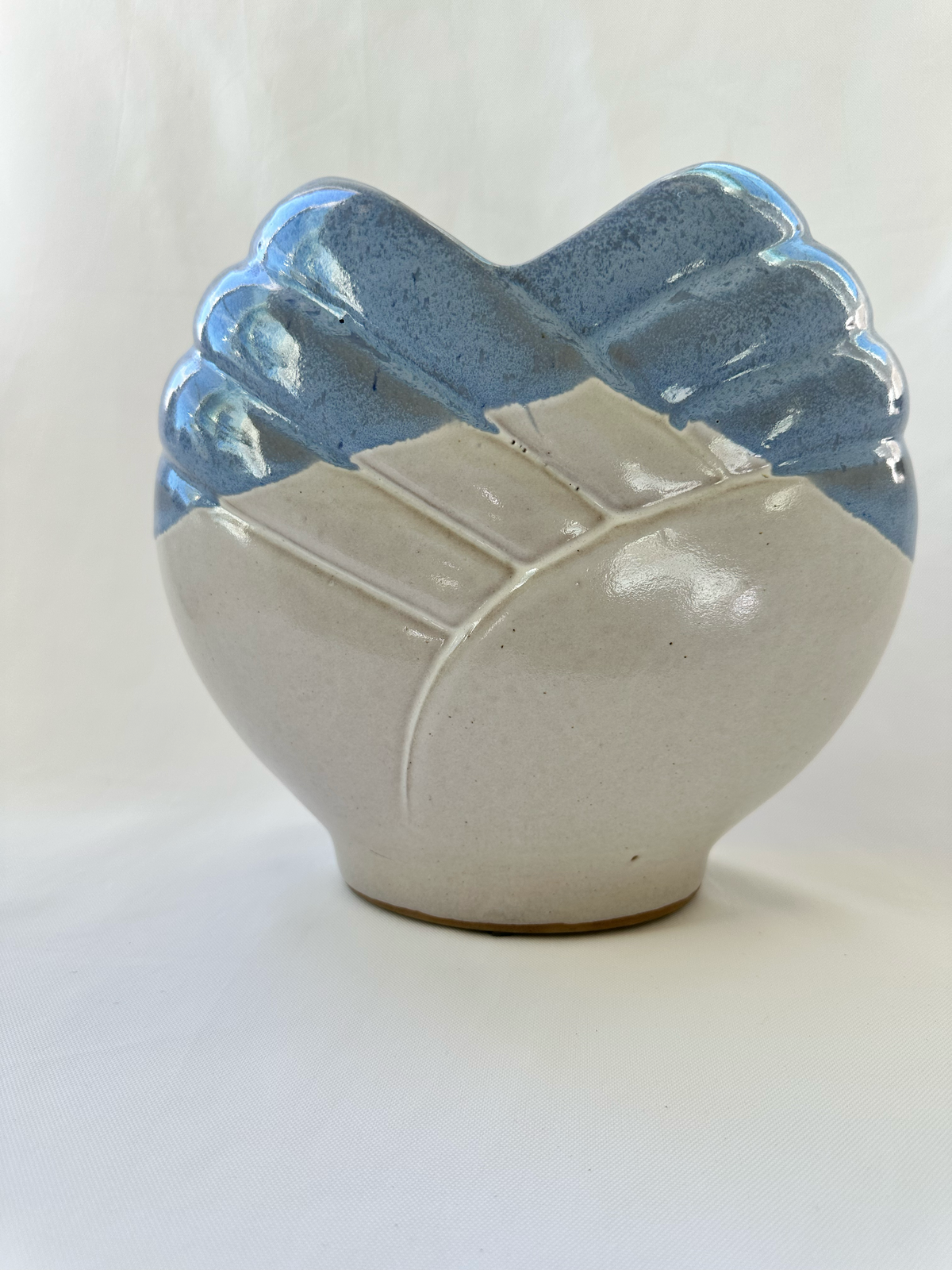 Back view of blue and off-white sculptural ceramic vase showing raised diagonal bands and mottled glaze.