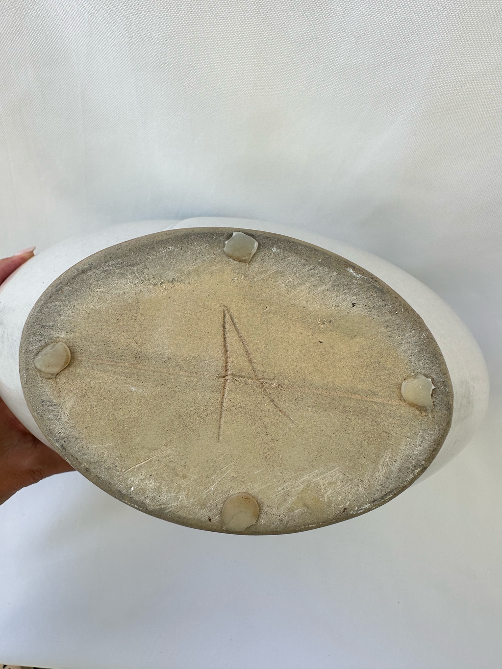 Bottom of ceramic vase showing the unglazed base and incised capital A maker mark.
