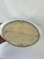 Bottom of ceramic vase showing the unglazed base and incised capital A maker mark.
