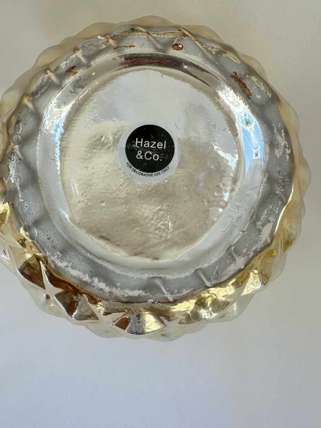 Close-up of wear and metallic-finish loss on the underside of Hazel & Co gold pineapple container.

