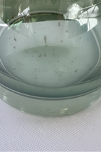 Close-up of lower green glass decanter body showing light gray spotting and interior discoloration near the base.
