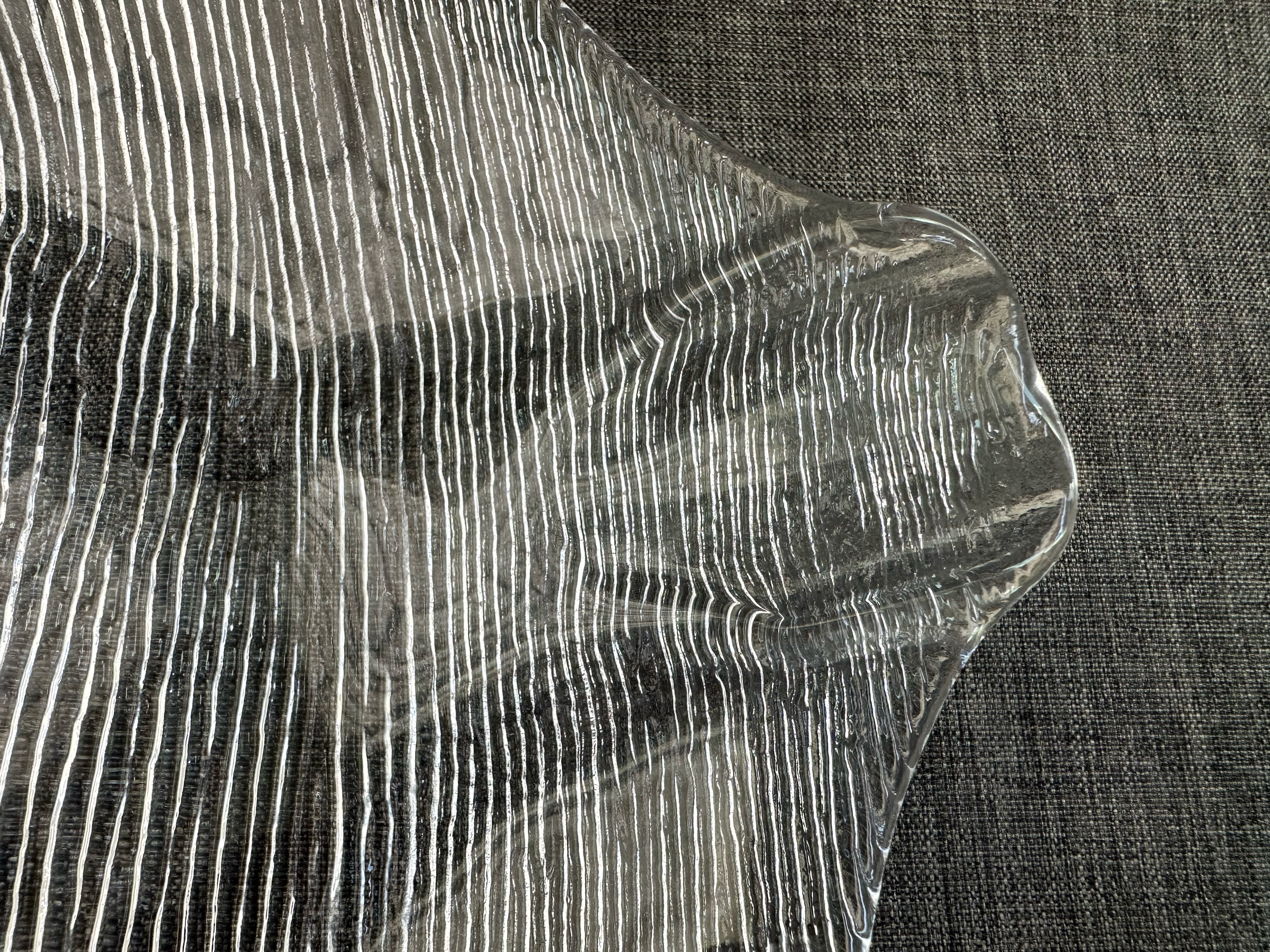 Close detail of linear bark-pattern texture across clear pressed-glass fish platter.
