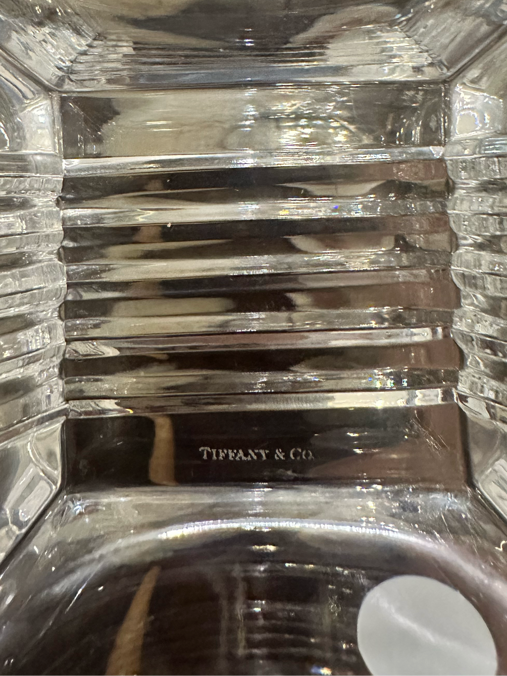 A close-up view of the inside of the bottom of a Metropolis crystal bowl showing the faceted interior with a laser etched Tiffany & Co. mark on the bottom. 