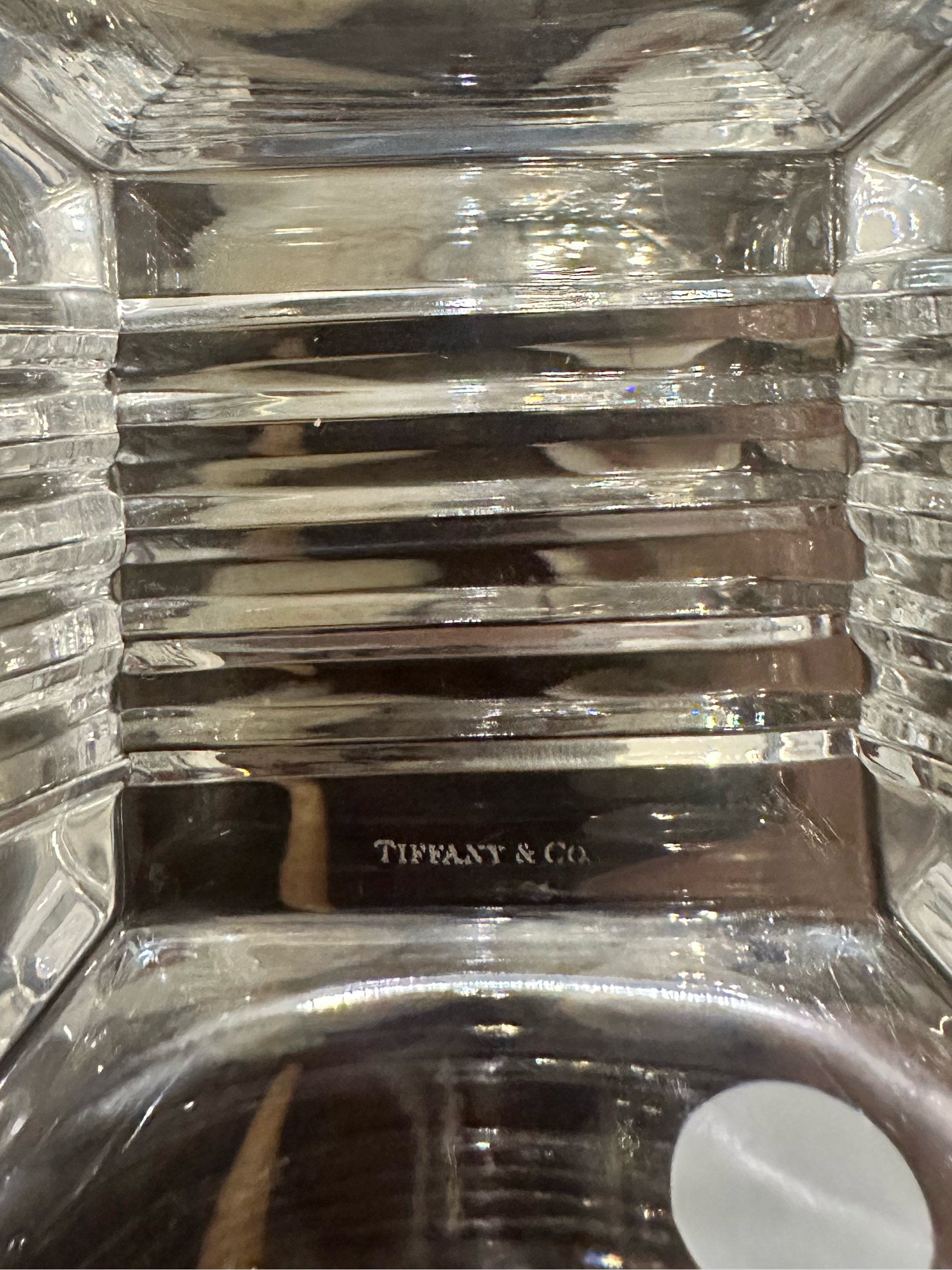 A close-up view of the inside of the bottom of a Metropolis crystal bowl showing the faceted interior with a laser etched Tiffany & Co. mark on the bottom. 