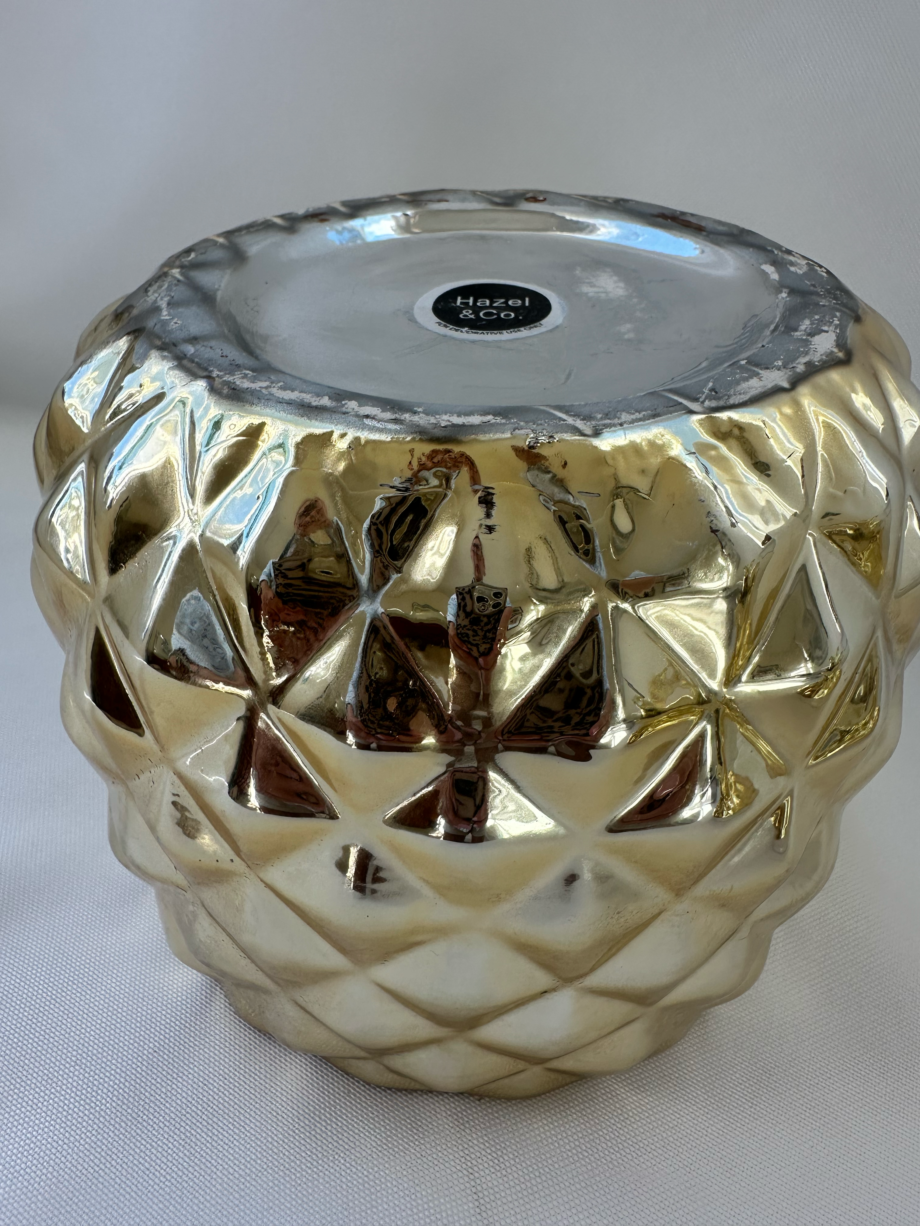 Close-up of wear and metallic-finish loss on the underside of Hazel & Co gold pineapple container.
