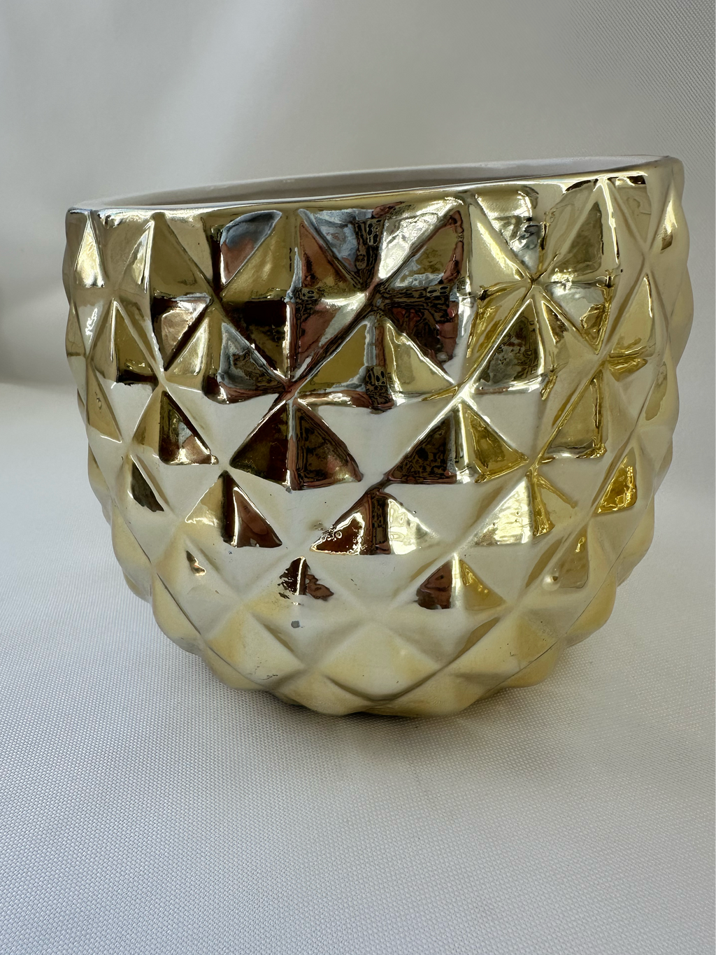 Side view of Hazel & Co gold ceramic pineapple container showing faceted geometric texture and reflective finish.
