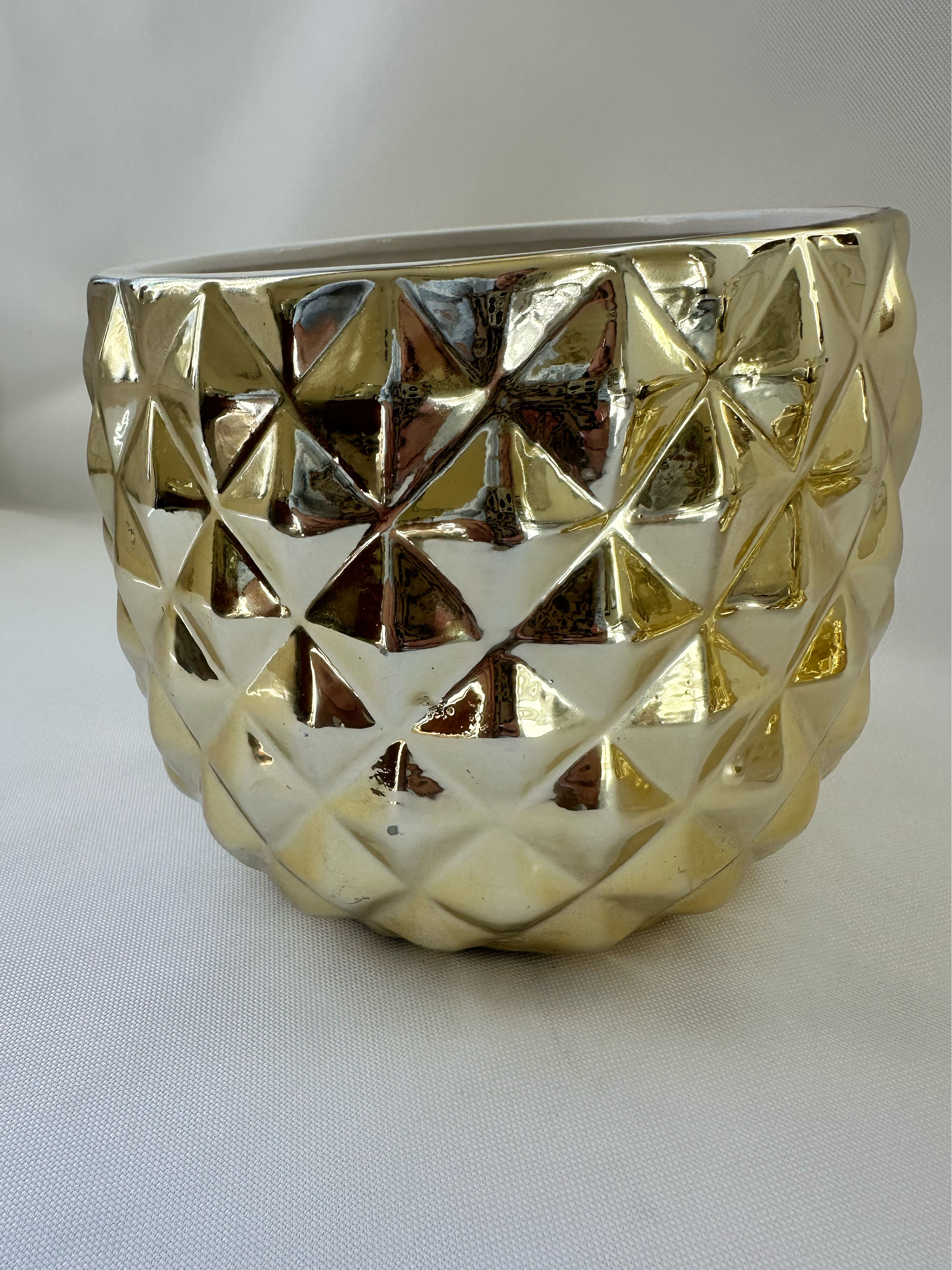 Side view of Hazel & Co gold ceramic pineapple container showing faceted geometric texture and reflective finish.

