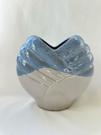 Front view of sculptural blue and off-white ceramic vase with heart-shaped opening and raised diagonal bands.