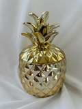 Hazel & Co gold-tone ceramic pineapple decorative container with faceted body and sculptural leafy lid.

