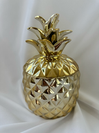Hazel & Co gold-tone ceramic pineapple decorative container with faceted body and sculptural leafy lid.
