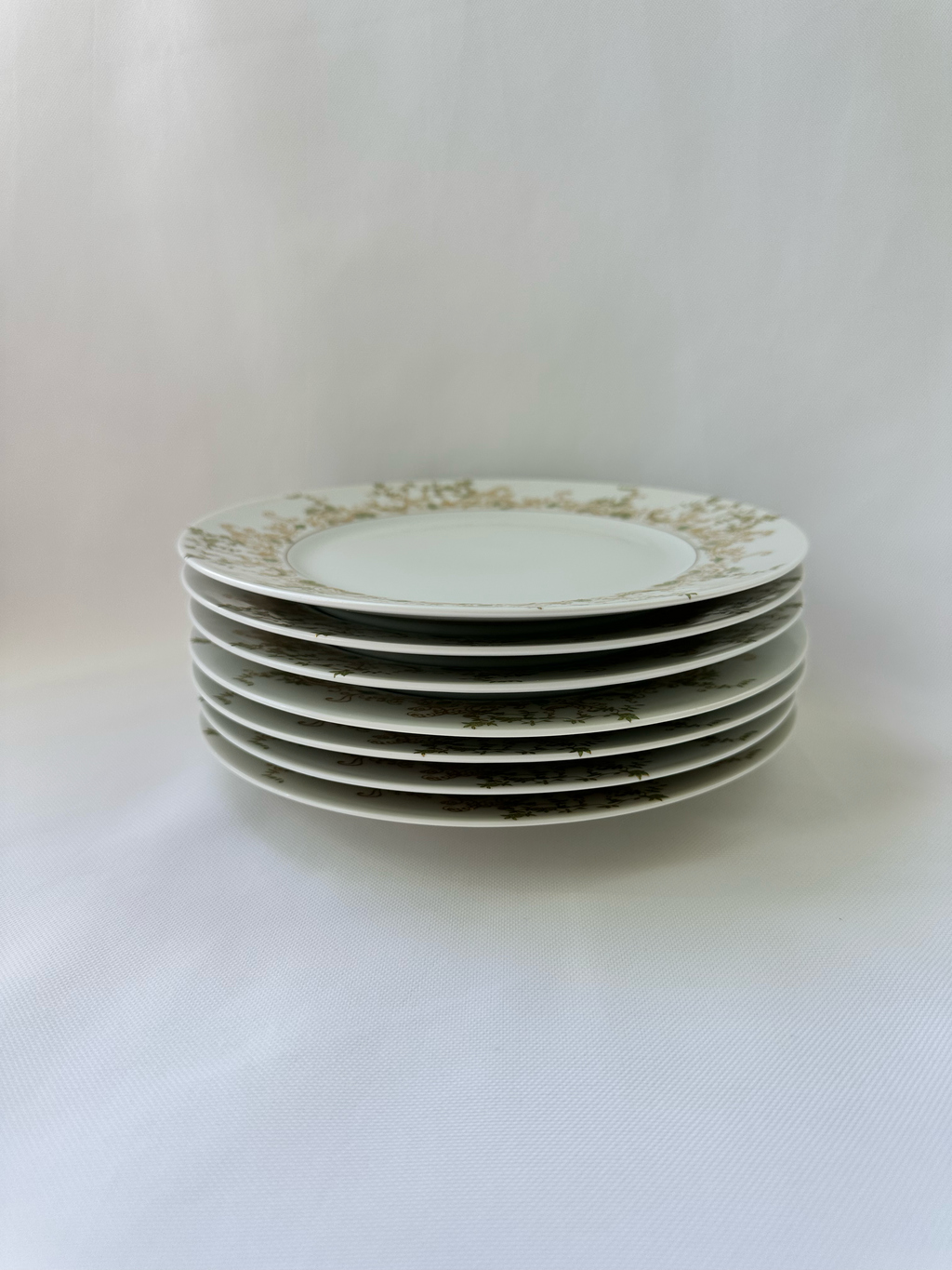 Stack of seven vintage Haviland Limoges Chambord plates showing the coordinated green and gold border pattern.

