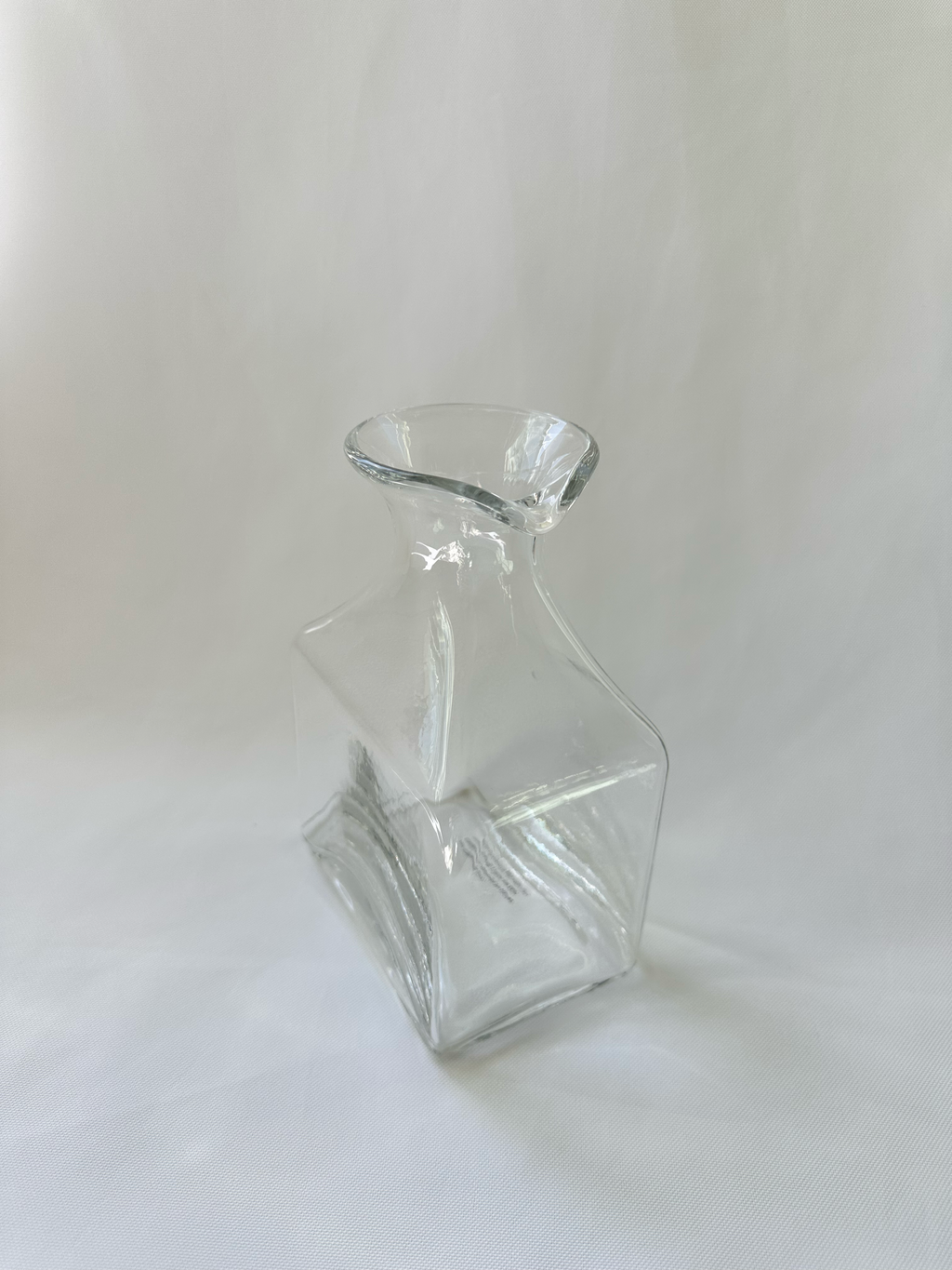 High angled view of clear glass vase showing the asymmetric opening and rolled glass rim.
