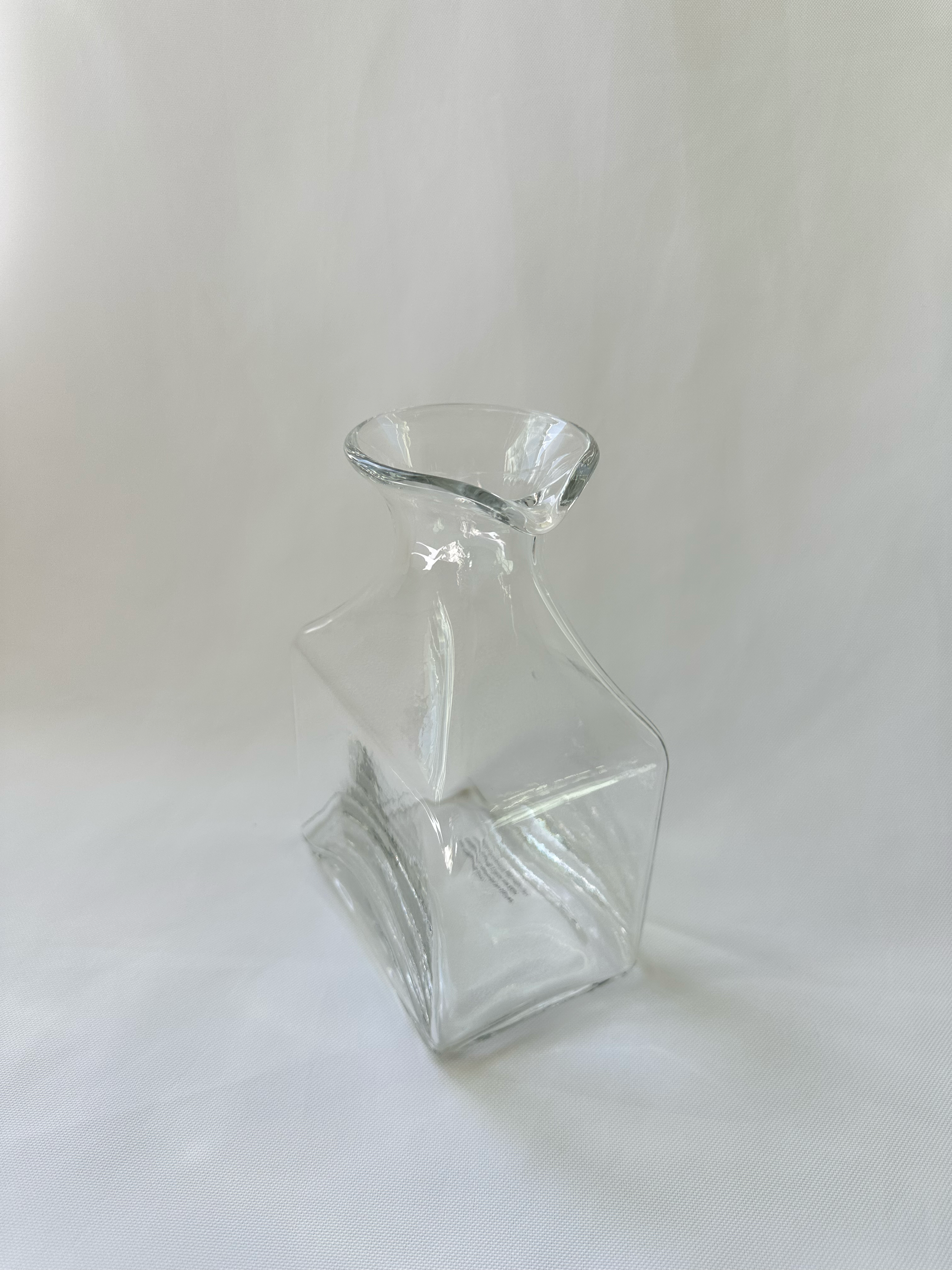 High angled view of clear glass vase showing the asymmetric opening and rolled glass rim.
