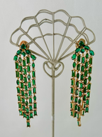Kate Spade Showtime green crystal fringe earrings hanging on display stand.
