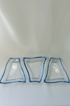 Front view of three coordinated clear glass sectional serving dishes arranged side by side.
