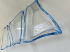 Angled close-up of three clear asymmetrical serving dishes highlighting their curved forms and blue glass edges.