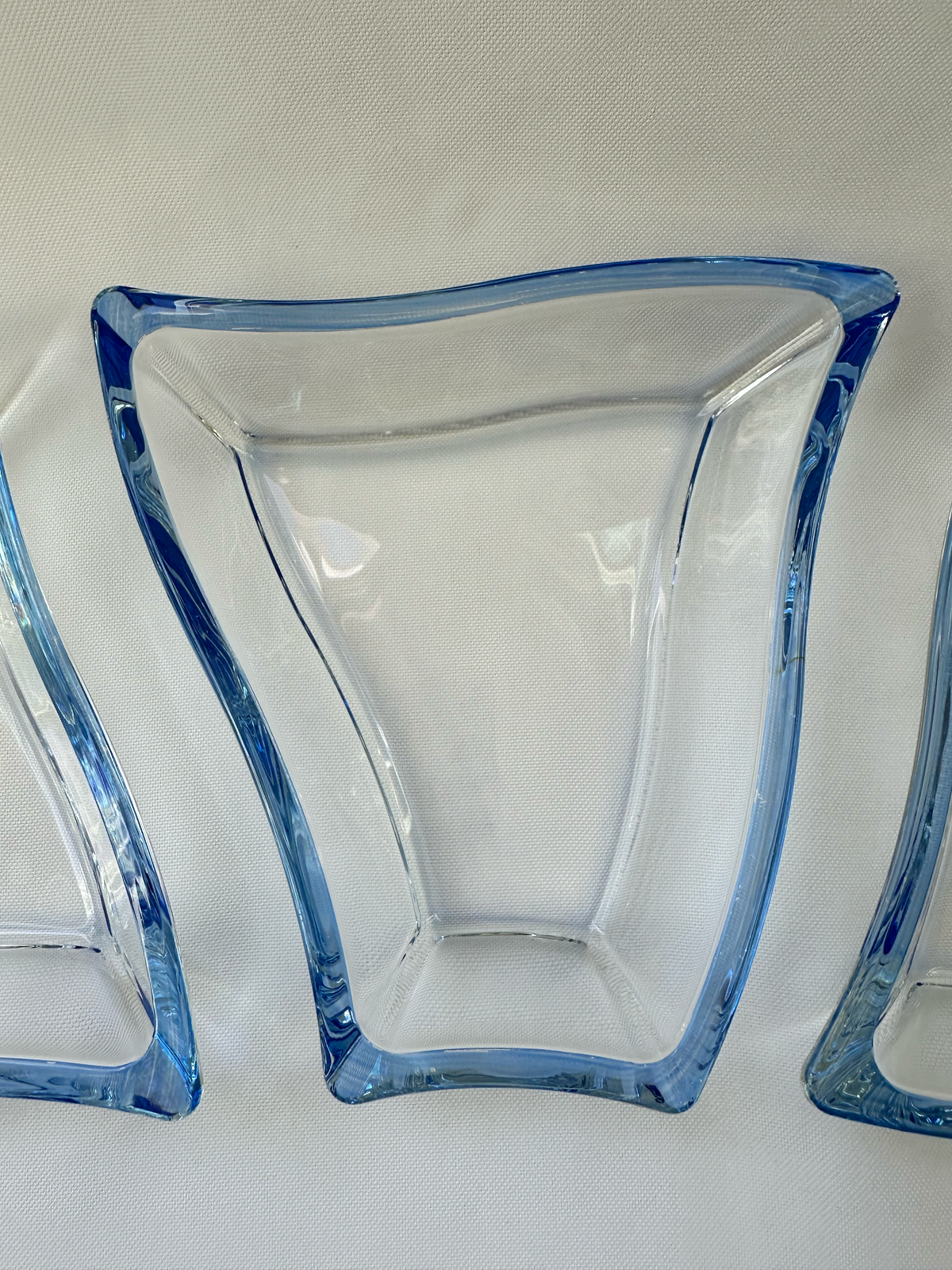 Close overhead view of one asymmetrical clear glass serving dish with a curved Sapphire blue perimeter.

