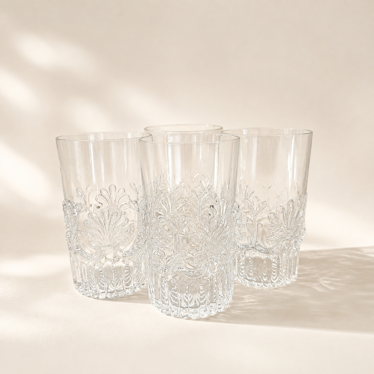 Set of four clear MMA-marked tumblers with raised fan and scroll decoration around the lower glass.
