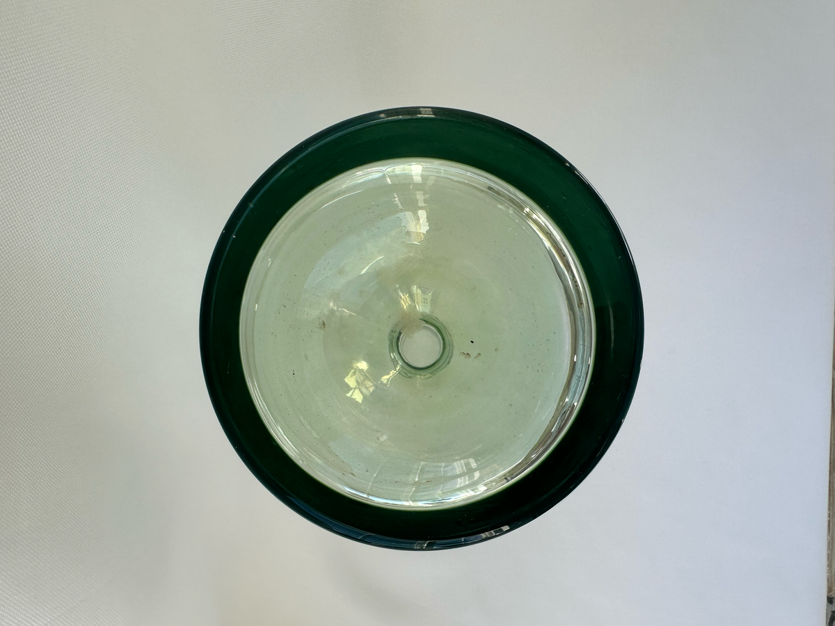 Overhead view into green glass decanter showing circular base and visible interior discoloration.
