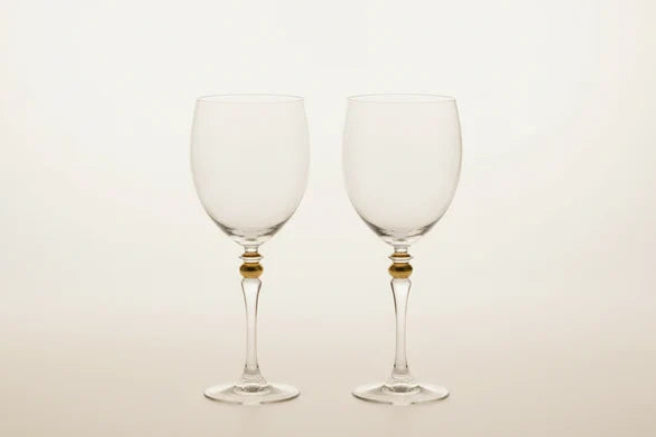 Two Luminarc France wine glasses with small gold bead accents at the base of the stems, standing side by side on a light beige background.