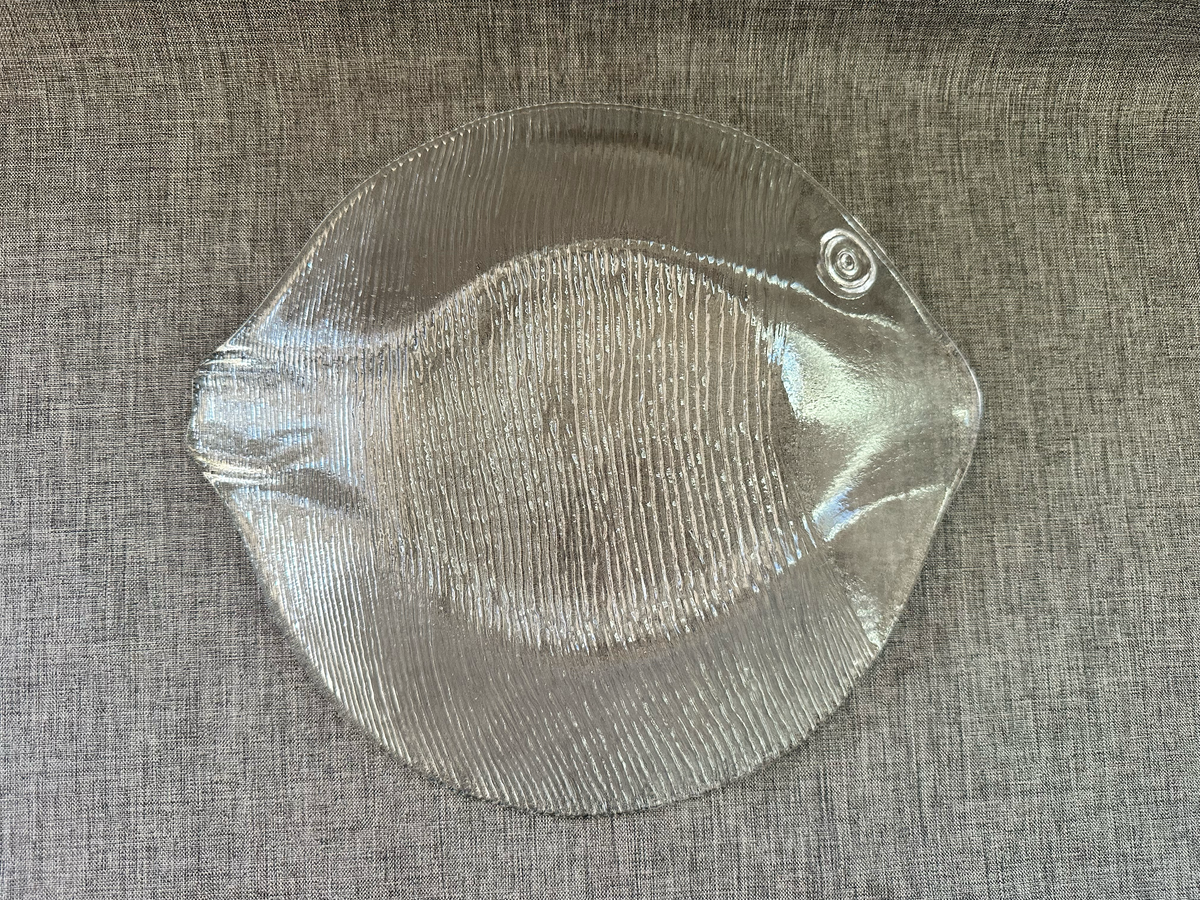 Underside detail of clear molded glass fish platter showing textured construction.

