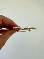 Side view of butterfly brooch held in hand showing its profile and pin clasp construction.

