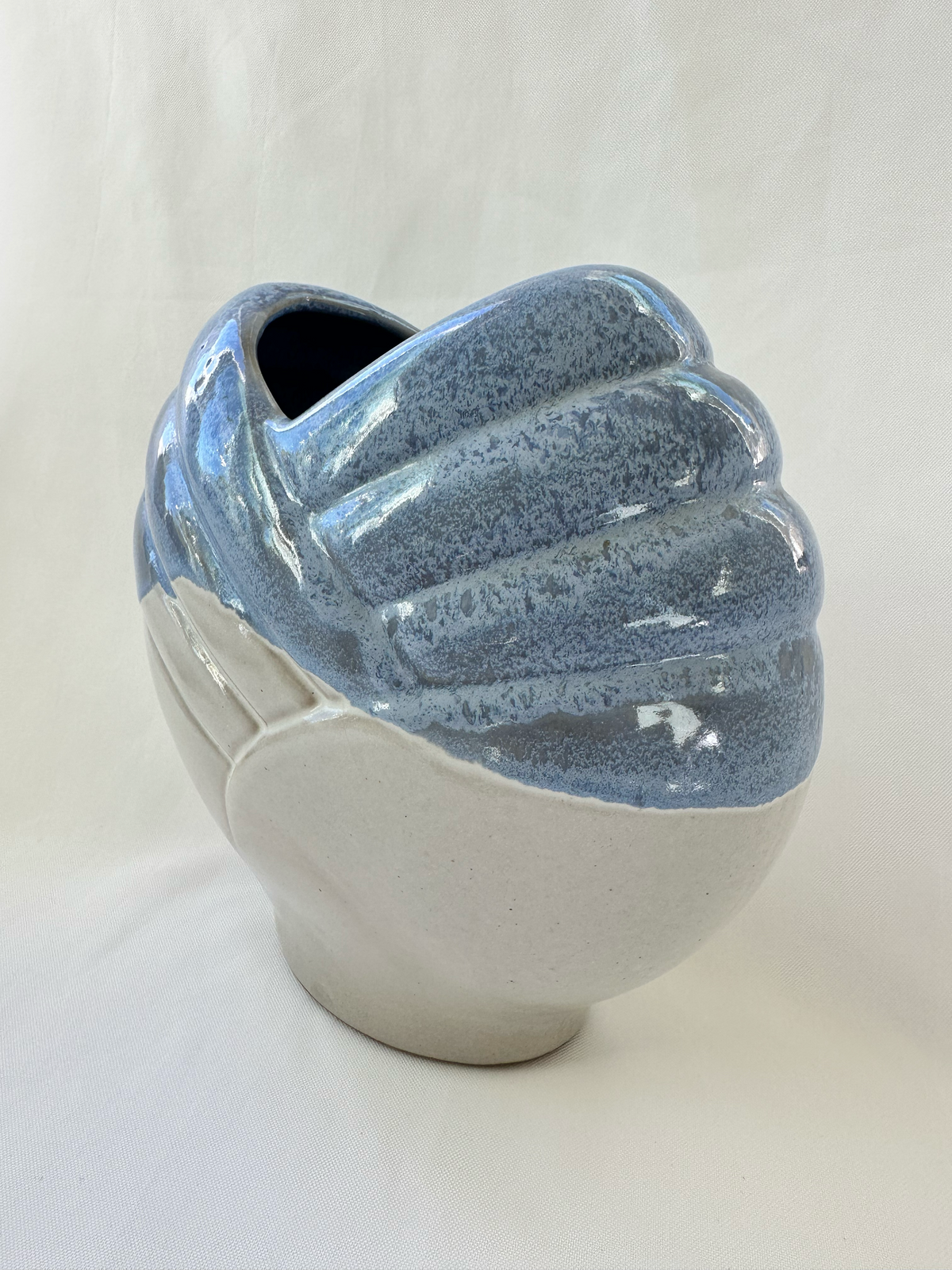 Three-quarter view of blue and off-white ceramic vase showing its narrow depth and sculptural profile.
