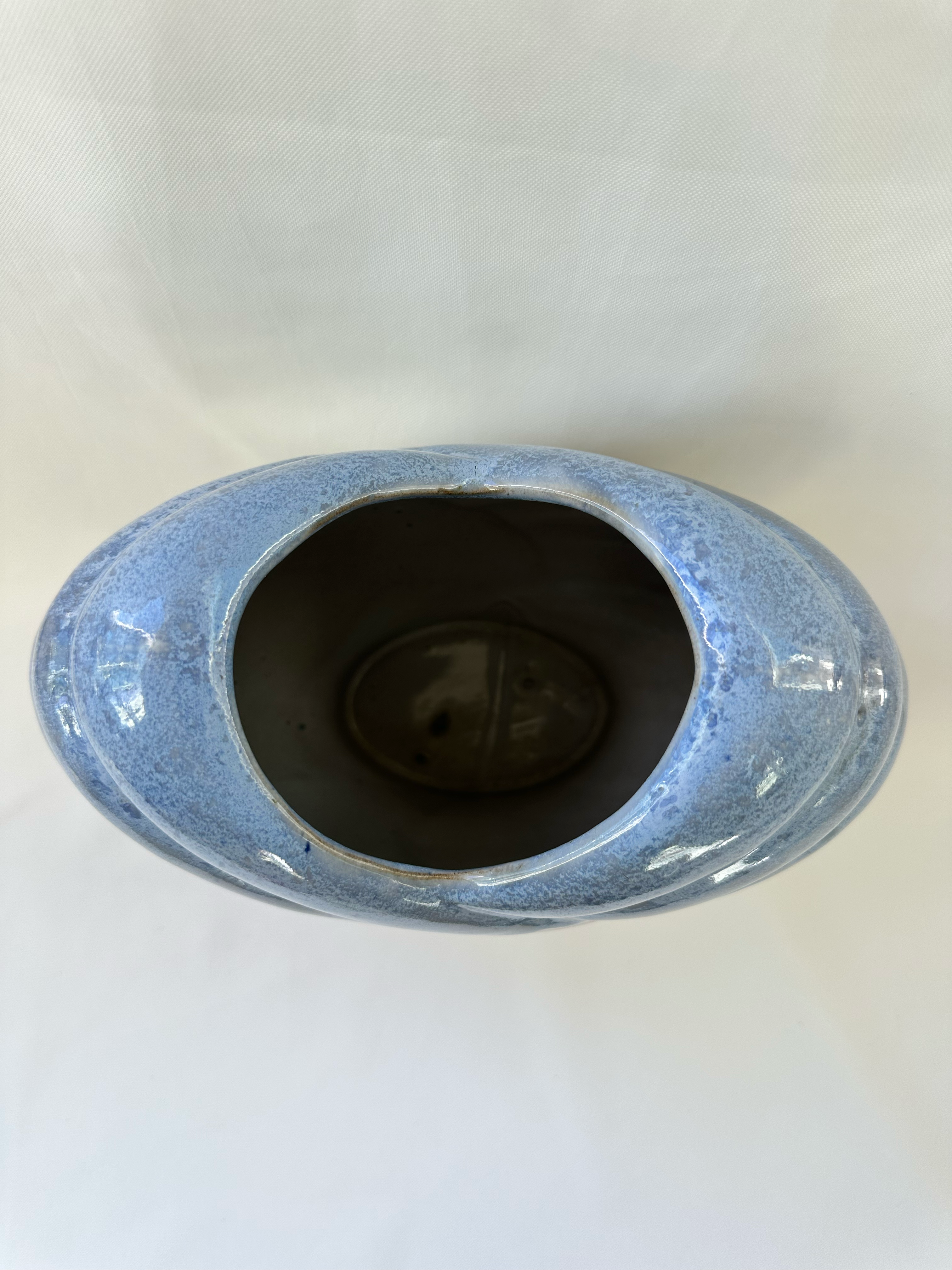 Overhead view of ceramic vase showing the heart-shaped opening and mottled pale-blue glaze.
