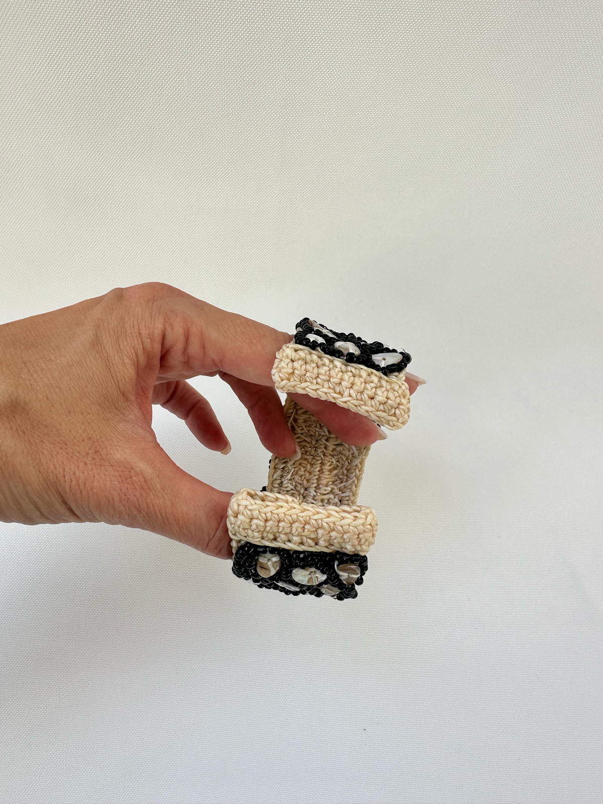 Open cuff bracelet held in hand to show scale, flexibility and the cream woven opening.
